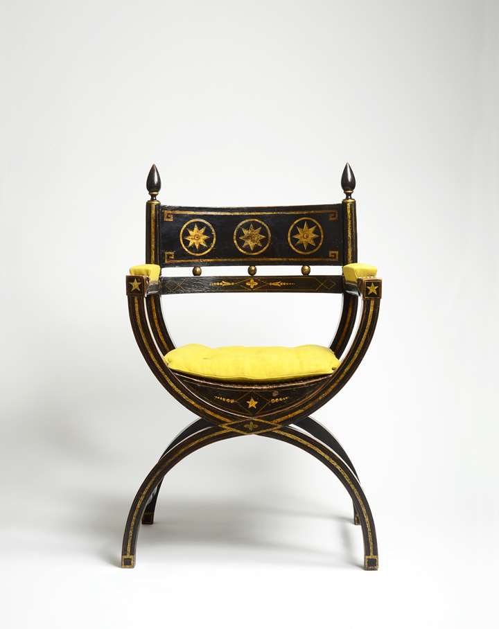 An impressive ebonised and gilt decorated X-framed armchair